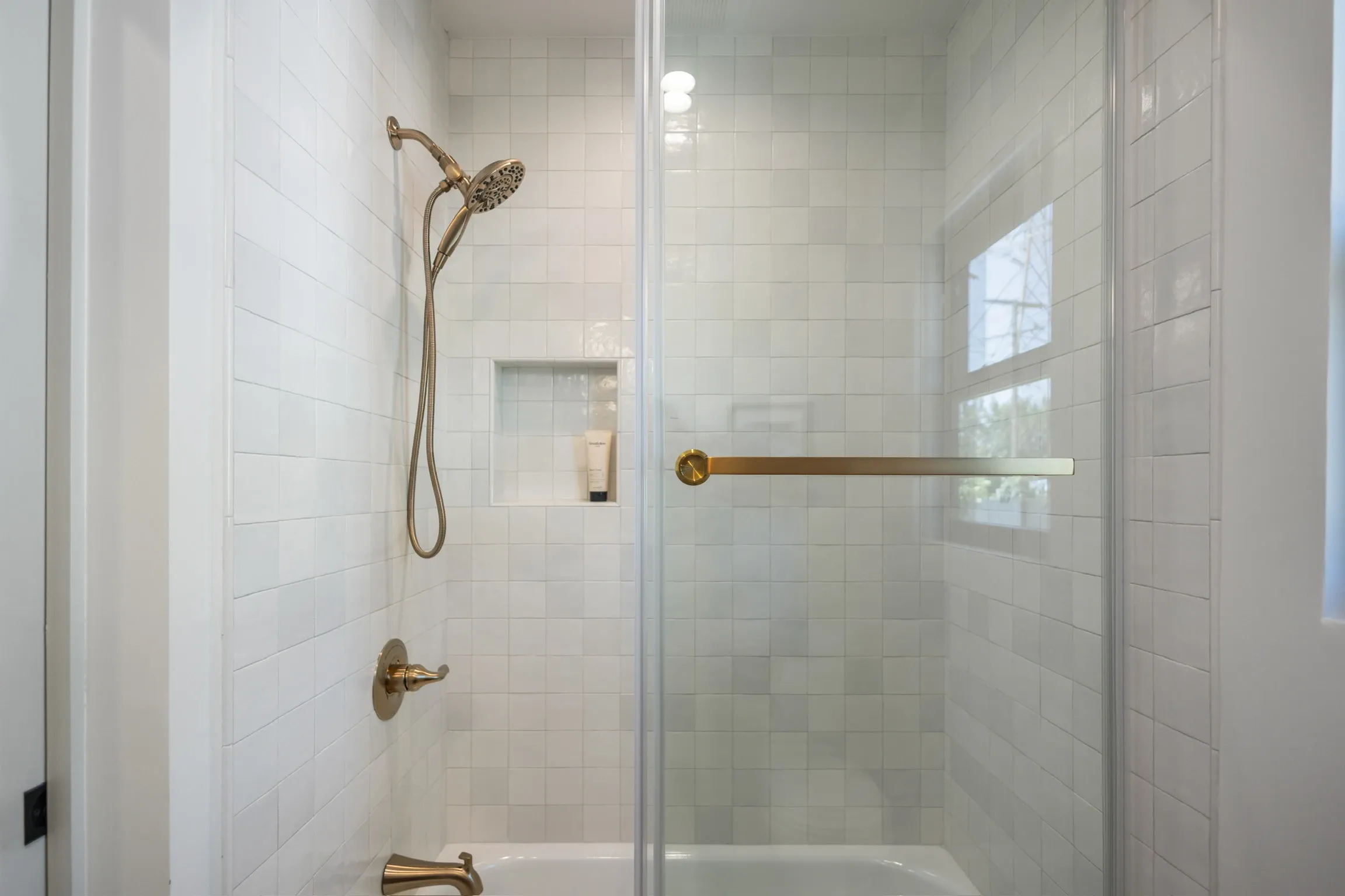 Walk-in shower with white zellige tile and brass fixtures