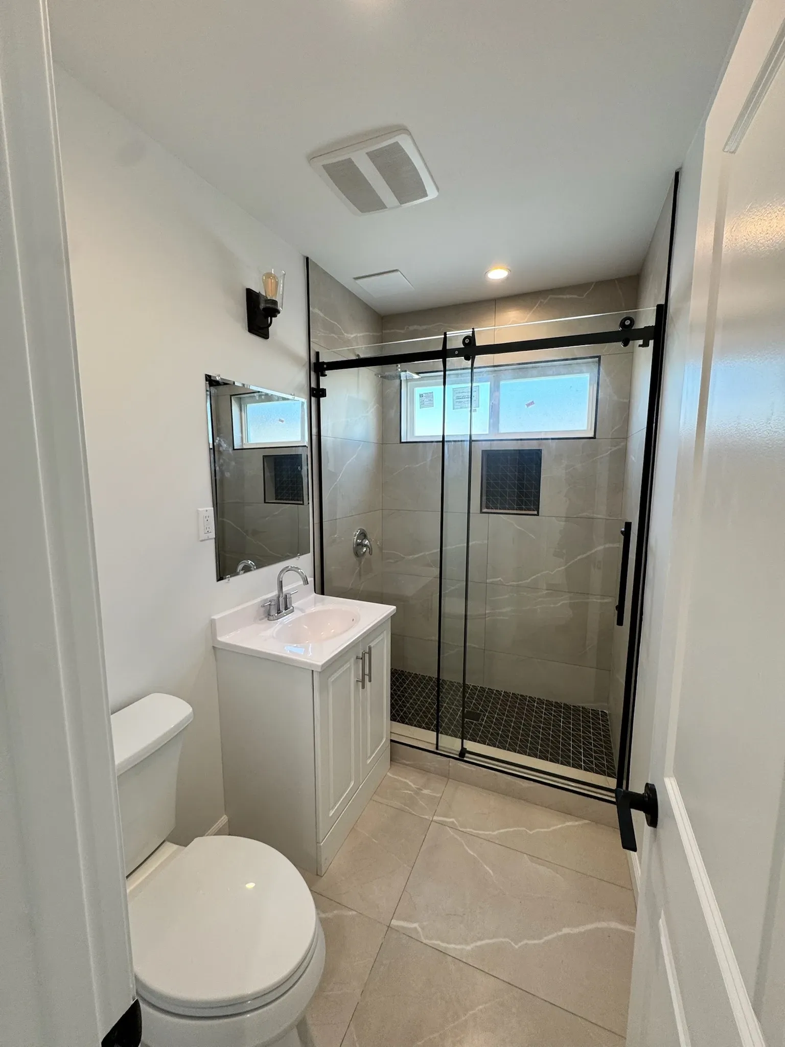 Walk-in shower with sliding glass door and large-format tile