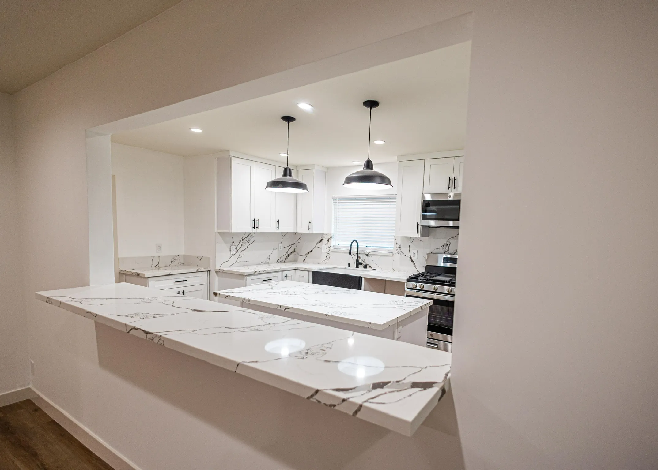 Open pass-through kitchen with marble backsplash and black fixtures
