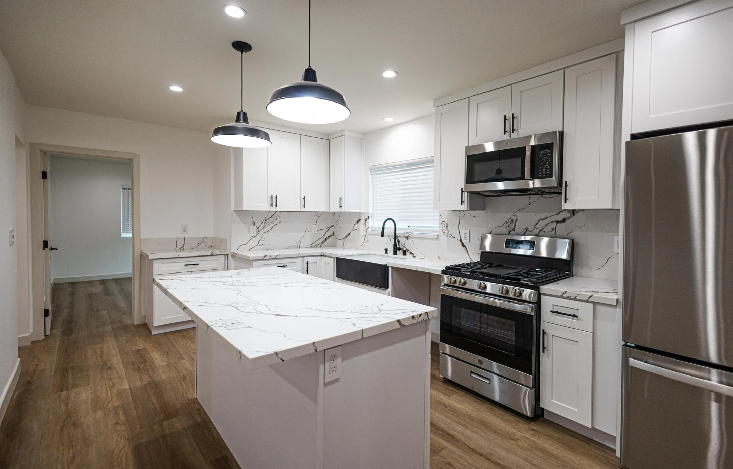 Remodeled kitchen with marble island, pendant lighting, and stainless appliances